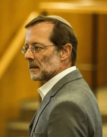 A distinguished man in a grey suit and glasses at an Istanbul local news event.
