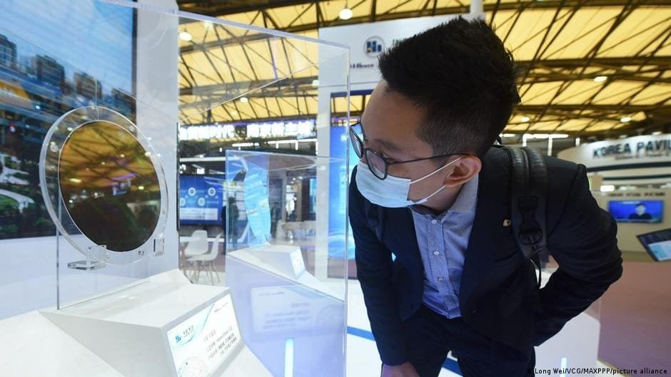 Young man examining advanced semiconductor chip at tech exhibition in Istanbul.