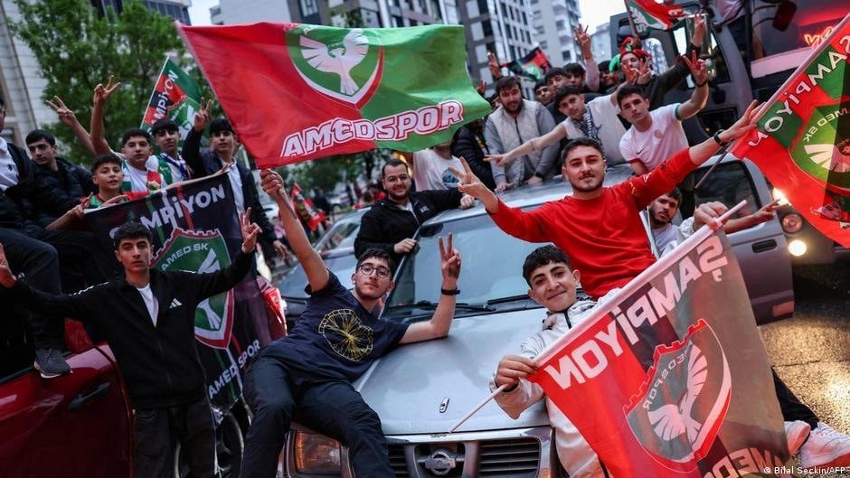 Fans celebrating Amedspor's success in the Super League with flags and enthusiasm.